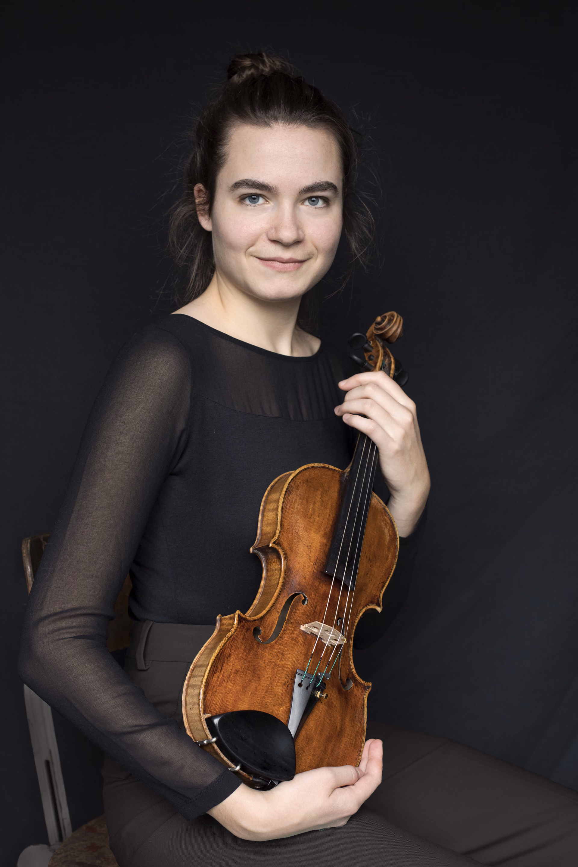 Hadewych with hair up, holding violin, looking into the camera
